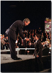 President George W. Bush holds the microphone for a boy during a town hall meeting in Ontario, Calif., Jan. 5. The President spoke about and listened to comments concerning the economy, immigration and the war in Afghanistan. White House photo by Eric Draper.