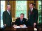 President George W. Bush signs the executive order establishing his Great Lakes Interagency Task Force, with EPA Administrator Michael Leavitt and James Connaughton, chairman of the Council on Environmental Quality, in the Oval Office Tuesday, May 18, 2004. The task force brings together ten agency and Cabinet officers to provide strategic direction on Federal Great Lakes policy, priorities and programs. White House photo by Paul Morse.