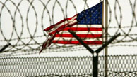 Eine amerikanische Flagge weht hinter einem Stacheldrahtzaun im Gefangenenlager Guantanamo