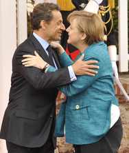 Nicolas Sarkozy fait une accolade à Angela Merkel lors de son arrivée; en arrière-plan, un soldat du détachement d'honneur salue.