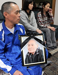 Kazuhiko Sato, left, carrying a portrait of his deceased father Kyugo, is pictured with his family members at a Tokyo home where they are taking shelter. (Mainichi)