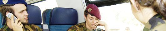 Drei Militärangehörige sitzen in einem Zugabteil, einer von ihnen telefoniert