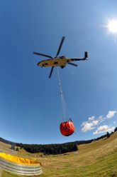 Helikopter leert ein «Bambi Bucket» (Löschwasser-Aussenlastbehälter) in ein Wasserbecken (Vergrösserung im neuen Fenster)
