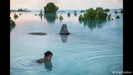 A young man in floods in Kiribati (Photo: Vlad Sokhin)